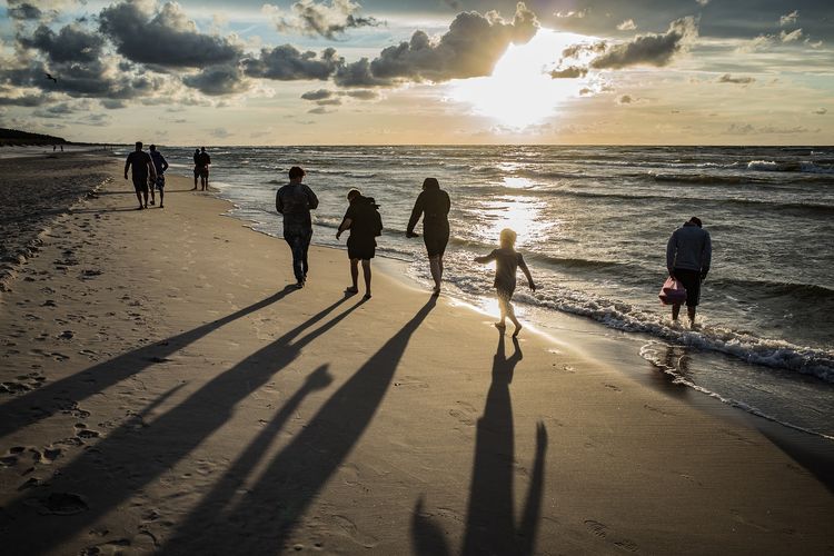 Bayangan manusia yang terbentuk di pantai karena cahaya matahari.