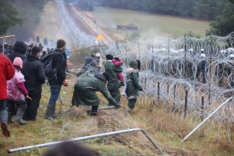 Para migran berada di perbatasan Belarus-Polandia di wilayah Grodno, yang dikelilingi pagar kawat berduri, Senin (8/11/2021). Polandia dan negara-negara Uni Eropa (UE) menuduh Belarus mendorong para migran untuk secara ilegal melintasi perbatasan sebagai pembalasan atas sanksi yang dijatuhkan UE kepada Minsk atas pelanggaran HAM.