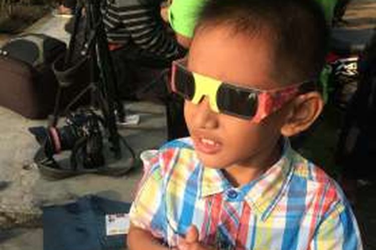 Salah satu anak di Pamekasan menyaksikan langsung gerhana matahari menggunakan kacamata khusus gerhana. 