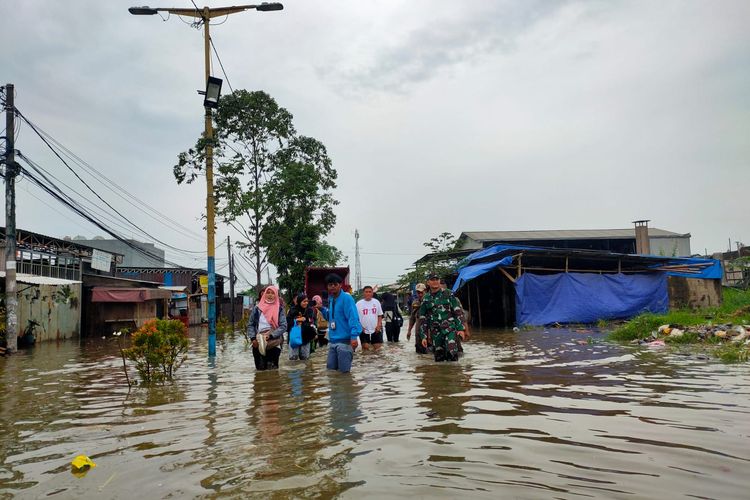 Masyarakat sedang berusaha berjalan di genangan banjir di Jalan Regency Periuk, Kota Tangerang terendam banjir hari ini, Rabu (15/3/2023).Banjir itu terjadi akibat hujan yang mengguyur Kota Tangerang sejak Selasa (14/3/2023) malam dan tanggul Kali Leduk jebol.