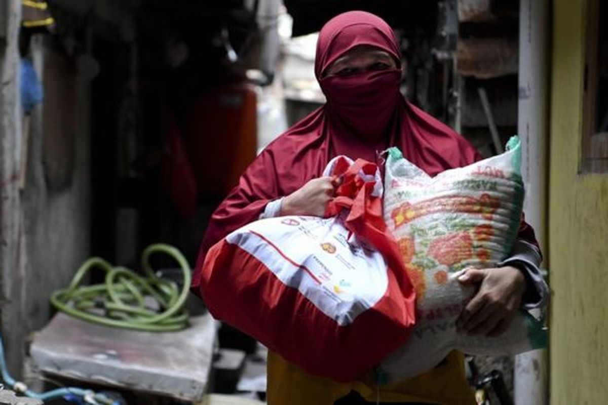 Warga membawa paket bantuan sosial dari pemerintah yang ia terima di kawasan Koja, Jakarta, Sabtu (02/05). 