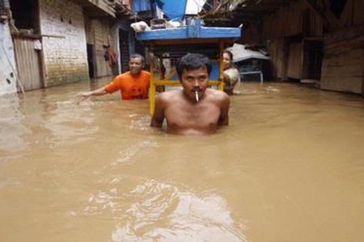 Warga memindahkan gerobak dagangan saat banjir merendam kawasan Kampung Melayu Kecil, Bukit Duri, Jakarta Selatan, Kamis (18/2/2010). Banjir luapan Sungai Ciliwung yang terjadi sejak dini hari tersebut mencapai ketinggian hingga dada orang dewasa. KOMPAS IMAGES/KRISTIANTO PURNOMO