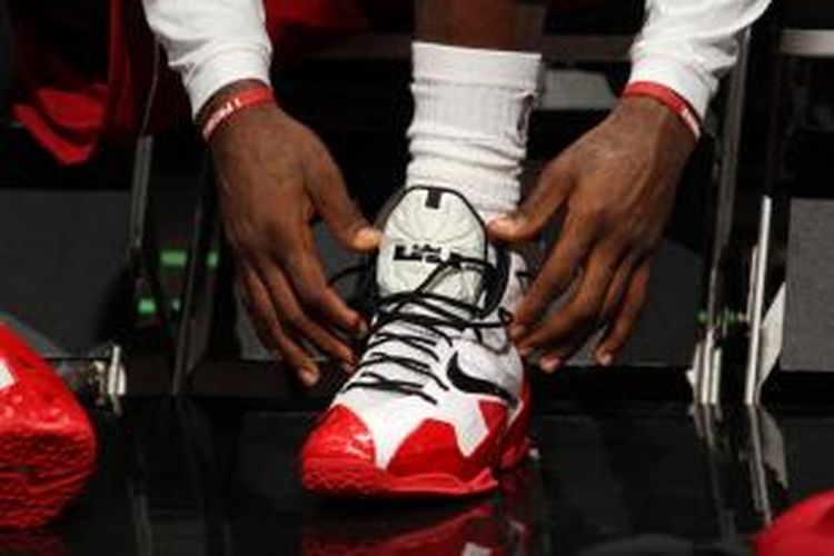 Pebasket Miami Heat, LeBron James membetulkan sepatu yang membalut kaki kiri yang mengalami cedera ankle, pada laga lanjutan kompetisi NBA melawan Utah Jazz di American Airlines Arena, Miami, Florida, Senin (16/12/2013).