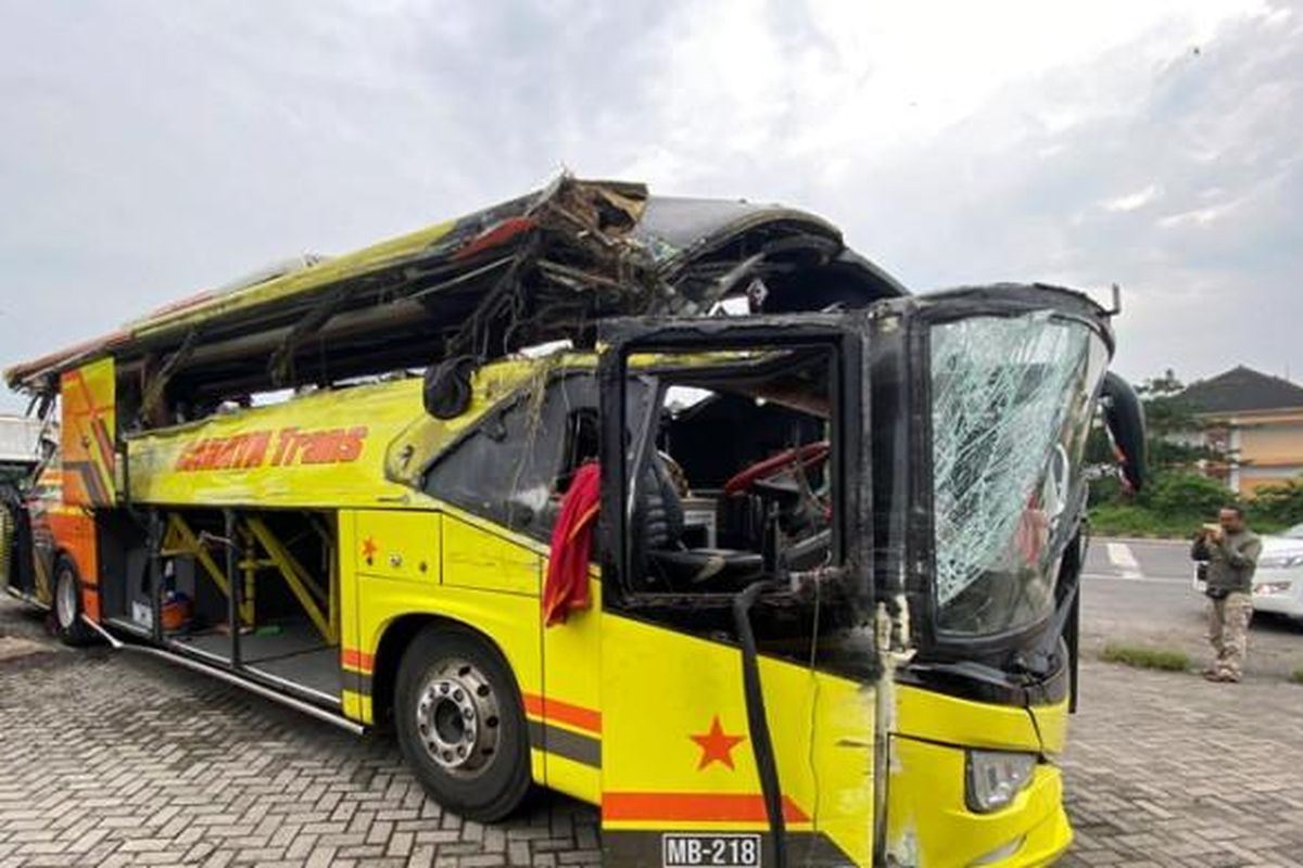 RINGSEK - Bus PO Cahaya Trans tampak ringsek parah di sisi kanan setelah dievakuasi ke depan Gerbang Tol Muktiharjo, Kota Semarang, dengan kaca depan bagian atas terlepas, seluruh kaca kanan pecah, serta kursi penumpang mengalami kerusakan. Bus tersebut sebelumnya mengalami kecelakaan tunggal di tikungan KM420A Simpang Susun Tol Krapyak, Kota Semarang, Senin (22/12/2025) dini hari, yang mengakibatkan 16 penumpang meninggal dunia.