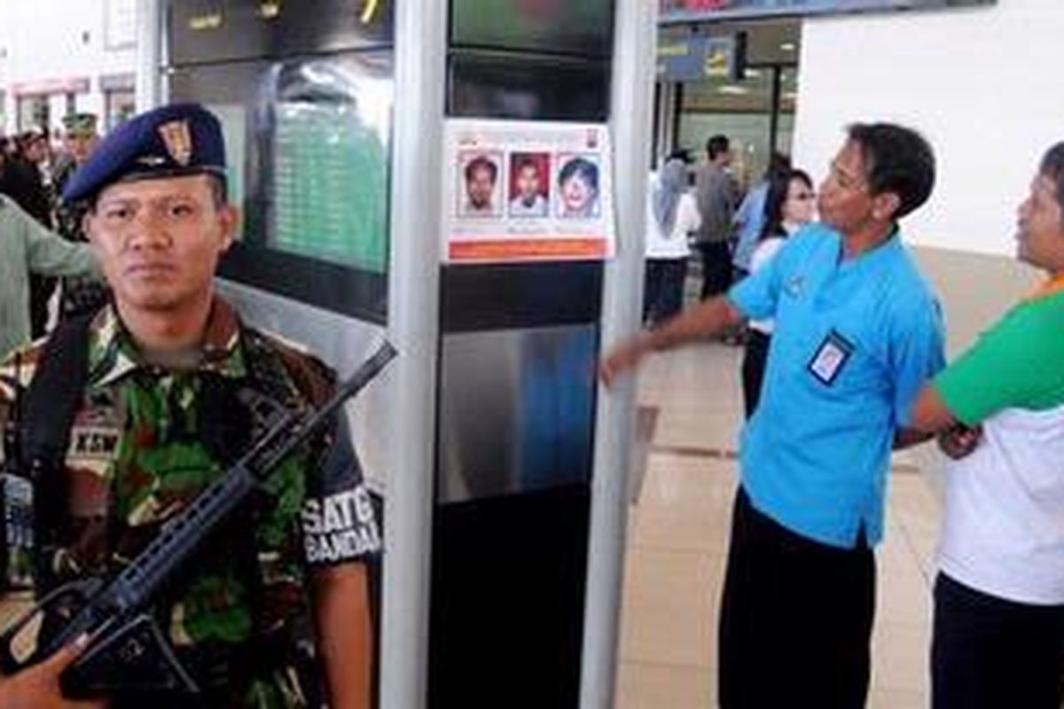 Anggota satgas PAM Bandara Internasional Juanda bersiaga di samping foto-foto daftar pencarian orang (DPO) di Bandara Internasional Juanda, Surabaya, Selasa (28/9/2010). DPO tersebut adalah Abu Tholut alias Mustofa, Taufik Hidayat, dan Jefri alias Kamal. Mereka diduga terlibat dalam perampokan Bank CIMB Niaga di Medan. 