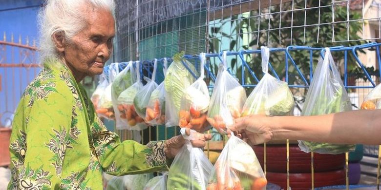 Seorang perempuan lansia mengambil bungkusan plastik berisi sayuran yang terletak di pertigaan kampung Kutu Wates, Desa Sinduadi, Kecamatan Mlati, Kabupaten Sleman, Daerah Istimewa Yogyakarta.