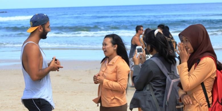 Pelajar sedang mempraktikkan bahasa Inggris dengan wawancarai turis asing yang juga peserta Pulau Merah Banyuwangi International Surfing Competition 2014, Jumat (23/5/2014).