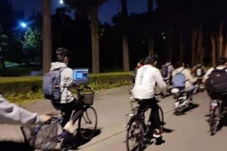 Dalam sebuah foto, seorang mahasiswa dari Universitas Tshinghua masih bekerja dengan laptopnya saat mengendarai sepeda.