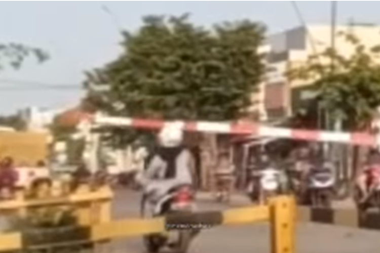 Tangkapan layar unggahan video yang memperlihatkan pengendara motor menerobos dan menabrak palang perlintasan kereta api yang sudah mulai tertutup.