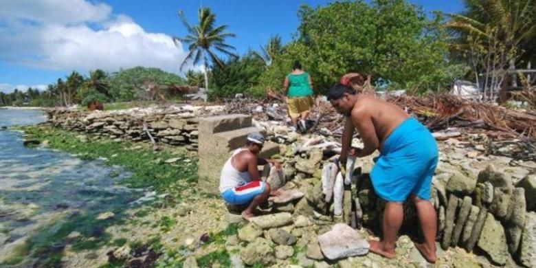 Foto ini menampilkan warga pulau Kiritimati, Kiribati tengah membangun tembok laut untuk mengurangi dampak ombak samudera Pasifik ke daratan. Kiribati adalah negara kepulauan kecil di Pasifik yang ketinggian rata-rata wilayah daratnya hanya beberapa meter di atas permukaan air laut. Akibat perubahan iklim, permukaan air laut meningkat dan membahayakan kehidupan di pulau-pulau kecil semacam Kiribati.