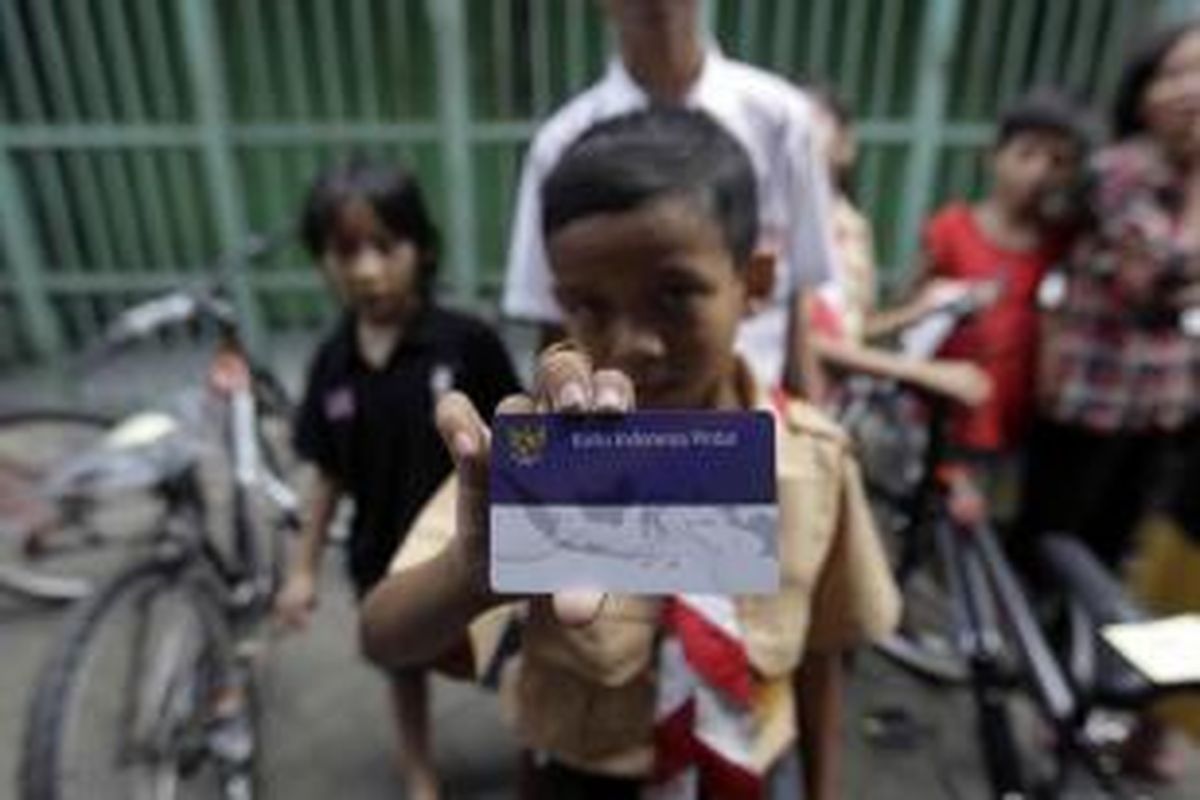 Warga menunjukkan Kartu Indonesia Sehat (KIS), Kartu Indonesia Pintar, dan Kartu Keluarga Sejahtera di Kantor Pos Kampung Melayu, Jalan Jatinegara Barat, Jakarta Timur, Rabu (13/5/2015).