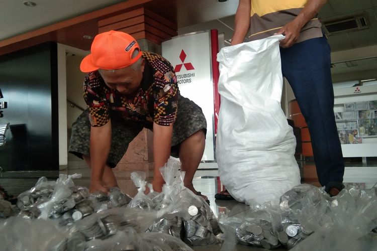 Muhammad Endang Junaedi, pengusaha jembatan penyeberangan perahu ponton di Kabupaten Karawang, Jawa Barat, tampak sibuk menata kumpulan uang koin Rp 500 yang dibawanya untuk membeli mobil, Kamis (7/4/2022).