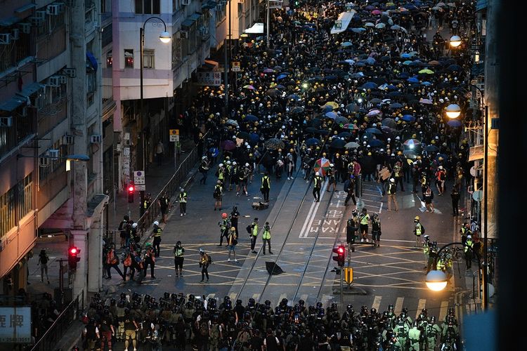 Massa pengunjuk rasa berhadap-hadapan dengan pasukan polisi anti-huru hara saat bentrokan di Hong Kong, Minggu (28/7/2019).