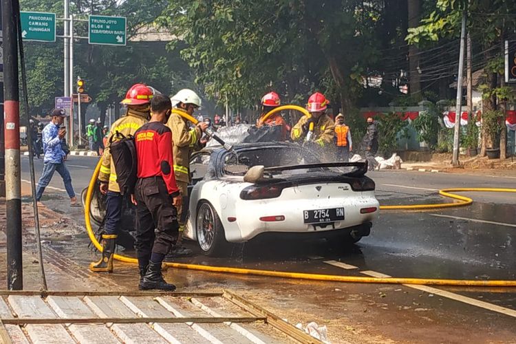Pemadam kebakaran memadamkan mobil sedan Mazda RX-7 keluaran 1996 yang terbakar di Jalan Suryo, Rawa Barat, Kebayoran Baru, Jakarta, Kamis (6/8/2020) pukul 09.15 WIB.