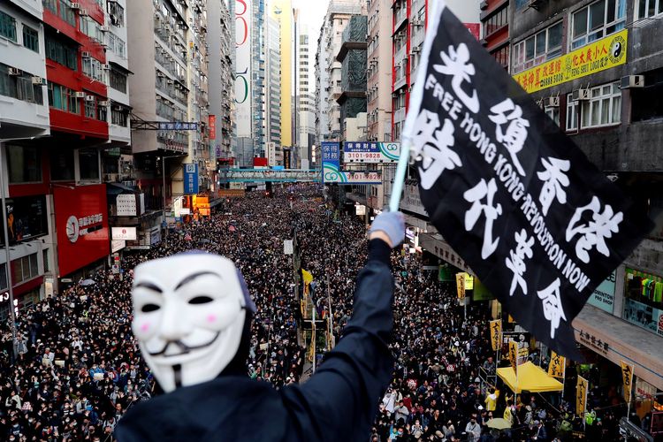 Seorang pengunjuk rasa memakai topen Guy Fawkes mengibarkan bendera saat demonstrasi Hari Hak Asasi Manusia, yang diselenggarakan oleh Civil Human Right Front, di Hong Kong, China, Minggu (8/12/2019).