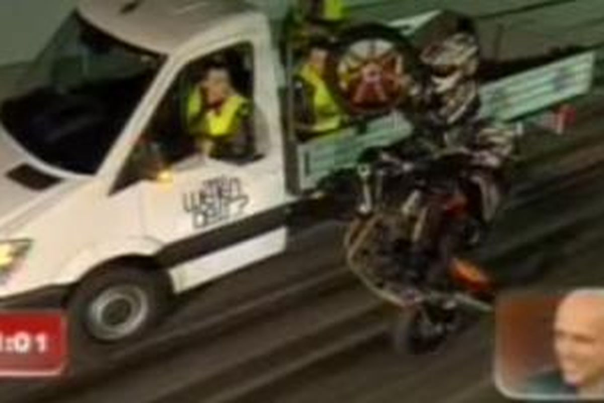 Dua stuntrider melakukan aksi mengganti ban depan sepeda motor sambil melakukan wheelie.