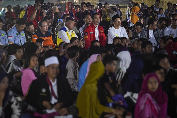 Presiden Joko Widodo (tengah) didampingi Gubernur NTB TGB Zainul Majdi (ketiga kanan) bersama warga korban gempa nonton bareng upacara penutupan Asian Games 2018 di Lapangan Kecamatan Gunungsari, Lombok Barat, NTB, Minggu (2/9/2018). Presiden Jokowi di sela kunjungannya ke lokasi gempa menyempatkan diri untuk nonton bareng warga korban gempa upacara penutupan Asian Games 2018.