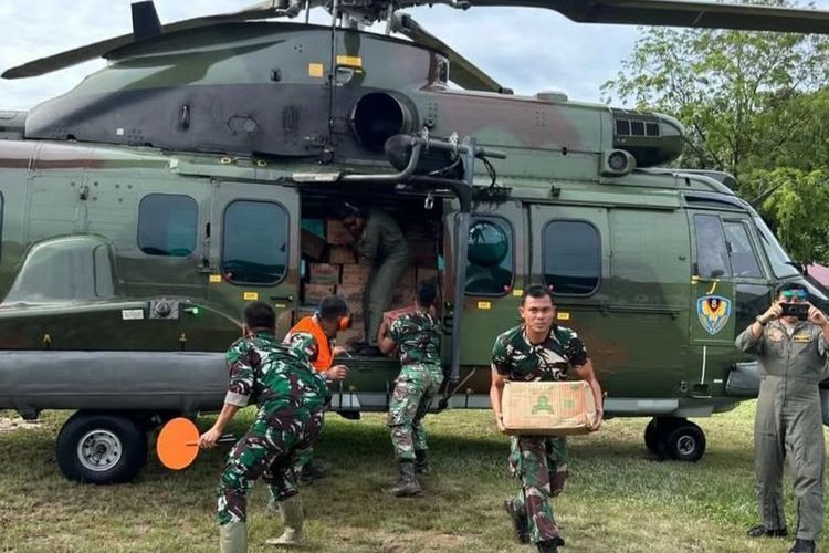 Prajurit TNI mengeluarkan bantuan dari helikopter yang terbang dari Jakarta menuju titik bencana banjir dan tanah longsor di Pulau Sumatera. 