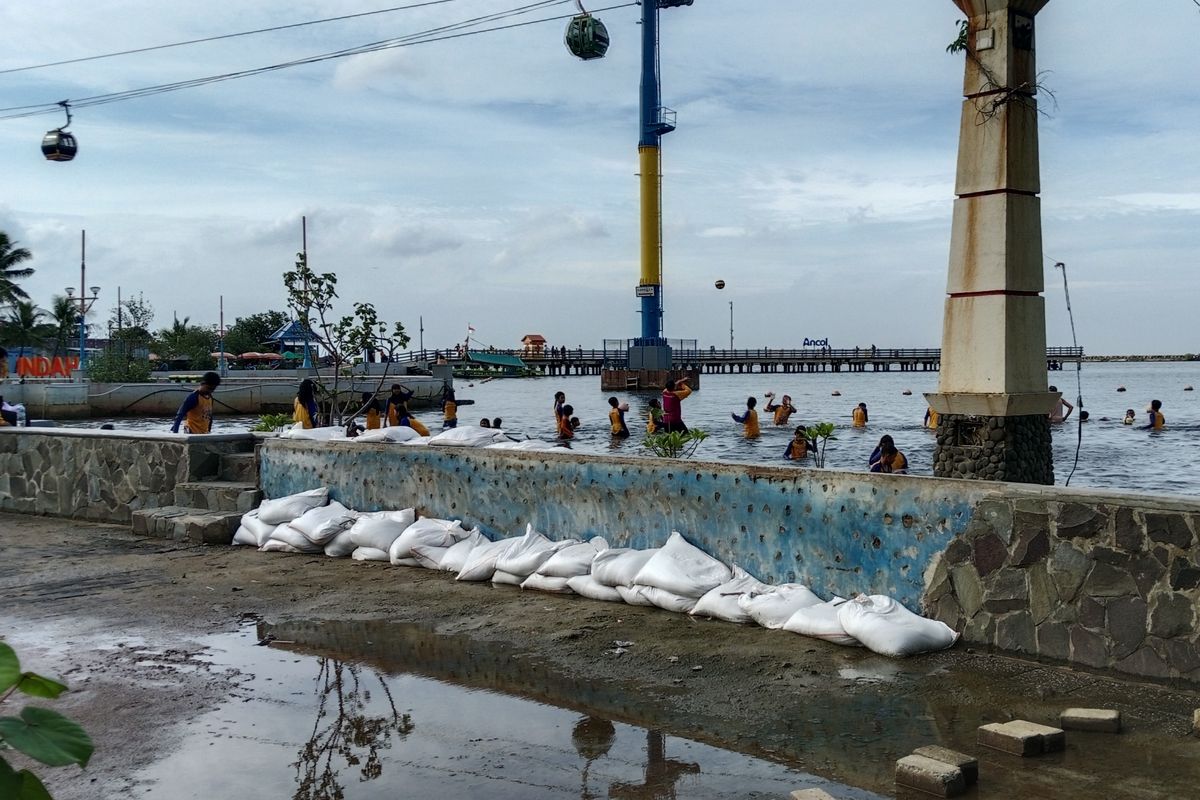 Tembok dinding di Pantai Indah, Ancol, Jakarta Utara telah dipasang penambal berupa karung-karung pasir untuk memperkuat dinding yang terdampak air pasang, Selasa (17/12/2024). 