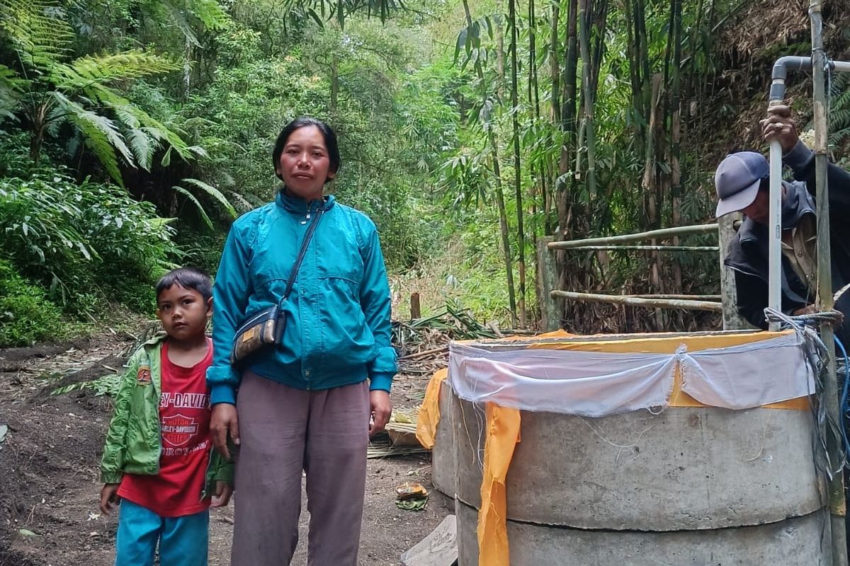 Wayan Rasmini bersama anaknya di depan sumur air di Konyel, Kintamani, Kabupaten Bangli. 