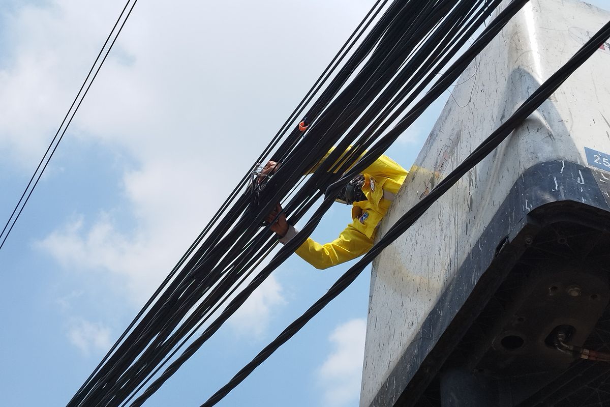 Petugas Dinas Bina Marga DKI menggunting pengikat kabel di lampu merah perempatan menuju Jalan Yusuf Adiwinata, Menteng, Jakarta Pusat, Rabu (9/8/2023). (KOMPAS.com/XENA OLIVIA)