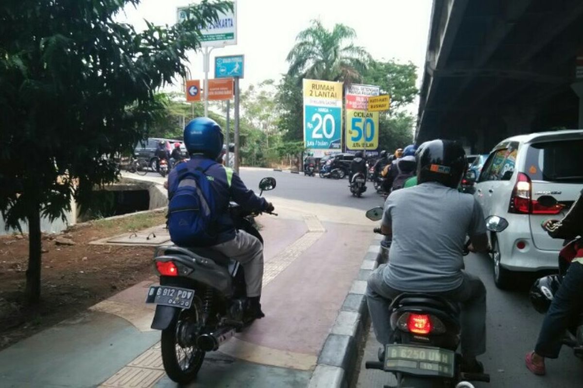 Pengendara motor nekat menaiki trotoar di Jalan Yos Sudarso, Jakarta Utara, Senin (11/9/2017).