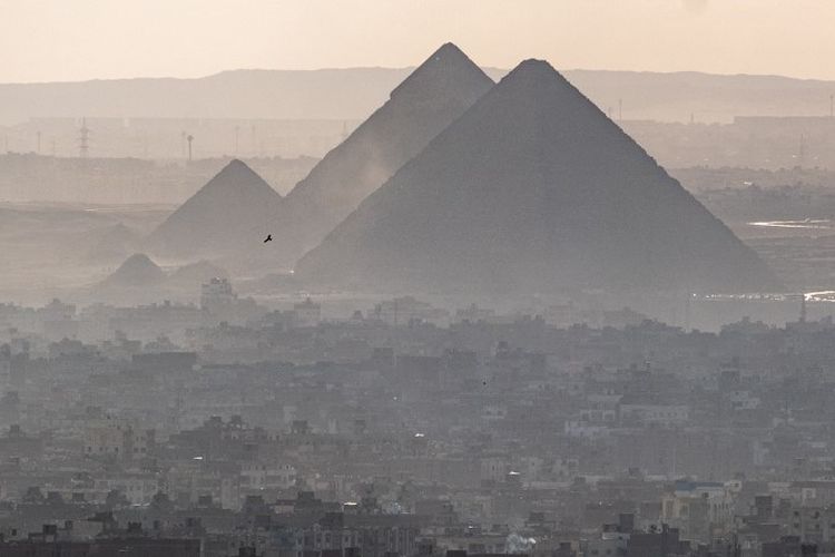 Seekor burung terbang di langit sebelum pekuburan piramida Giza di kota kembar Giza, ibu kota Mesir, pada 13 Januari 2022.