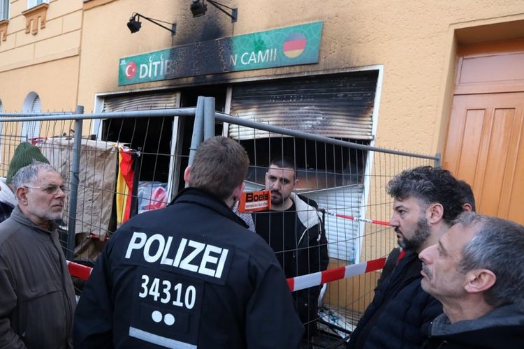 Petugas kepolisian Jerman berbicara dengan anggota masjid Koca Sinan Camii di Berlin yang menjadi sasaran bom molotov, Minggu (11/3/2018).