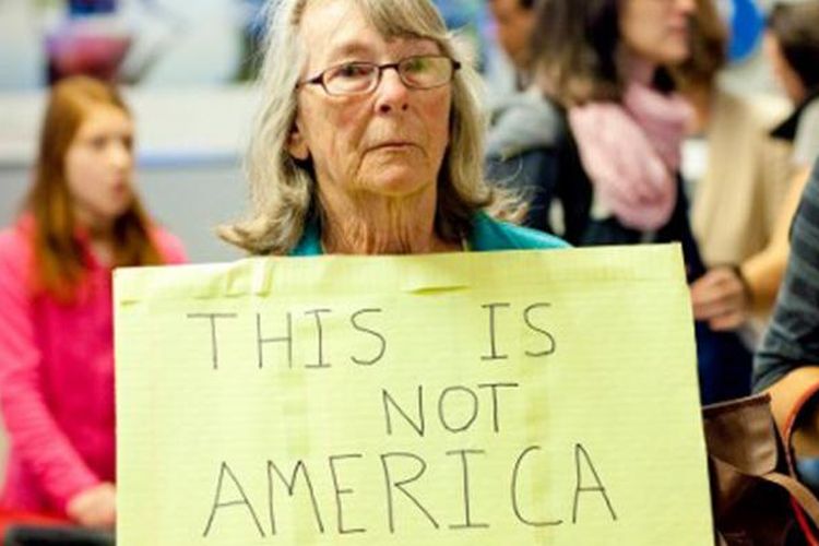Seorang warga, Judy Lewis dari San Juan Capastrano, California memegang tulisan di depan Bandara Internasional Los Angeles, untuk menentang kebijakan anti imigran Presiden Donald Trump.  