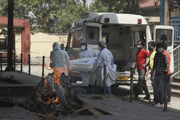 Pekerja medis membawa jenazah korban Covid-19 di krematorium New Delhi, India, pada 19 April 2021. Ibu kota India itu menerapkan lockdown sejak Senin malam untuk mencegah kolapsnya sistem kesehatan.