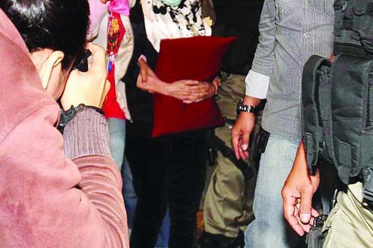 Buronan Komisi Pemberantasan Korupsi, Nunun Nurbaeti (mengenakan kacamata dan masker), keluar dari Gedung KPK di Jalan  HR Rasuna Said, Jakarta, seusai menjalani pemeriksaan kesehatan, Minggu (11/12) dini hari. Nunun kemudian ditahan di Rumah Tahanan Pondok Bambu, Jakarta Timur.