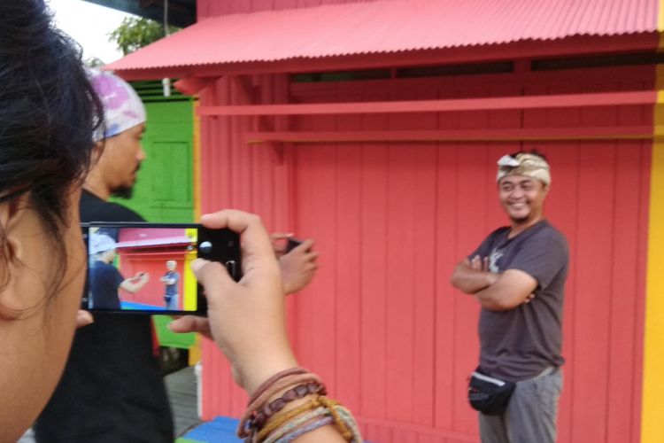 Wisatawan berfoto di depan rumah yang dikenal dengan Kampung Pelangi di Kota Pangkalan Bun, Kotawaringin Barat, Kalimantan Tengah, Sabtu (17/2/2018). Kampung Pelangi merupakan salah satu obyek wisata buatan yang kini dikembangkan oleh Pemerintah Kabupaten Kotawaringin Barat untuk menarik kunjungan wisatawan nusantara maupun mancanegara.