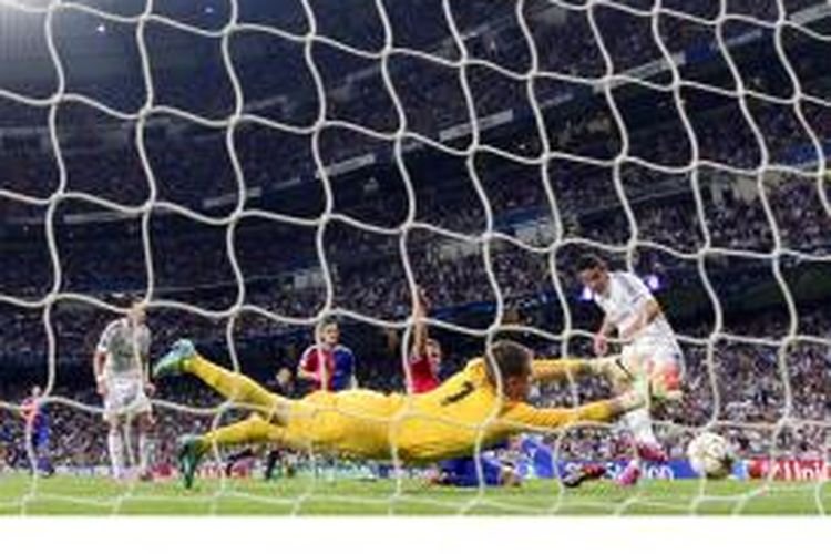 Gelandang Real Madrid, James Rodriguez (kanan), mencetak gol ke gawang Basel yang dikawal Tomas Vaclik, dalam matchday pertama penyisihan Grup B Liga Champions di Santiago Bernabeu, Selasa (16/9/2014).