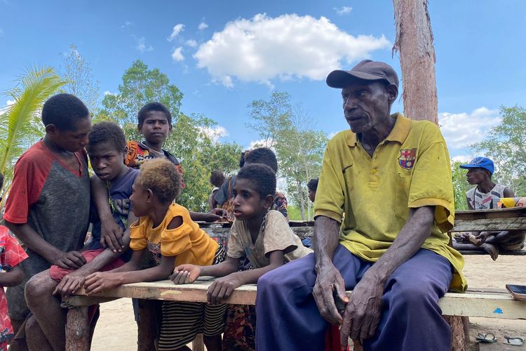 Ketua Suku Adat Kanum Papua Nugini, Silasianay (baju kuning bertopi) saat duduk santai bersama seorang Ibu bernama sekelompok anak-anak di belakang PLBN Sota, Merauke, Papua Selatan, Senin (13/11/2023).  