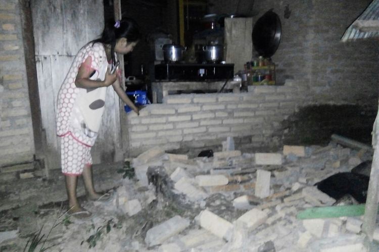 Seorang warga terlihat di samping dinding bata yang roboh di rumahnya di desa Tobadak di Mamuju Tengah, Sulawesi Barat, Jumat (28/9/2018), setelah gempa bermagnitudo 7,4 menghantam daerah tersebut.