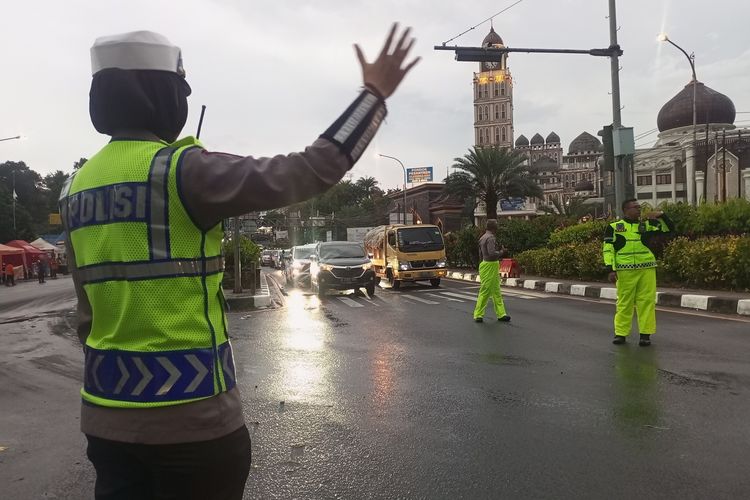 Petugas kepolisian sedang menormalkan arus lalu lintas setelah diberlakukan one way di ruas Jalan Raya Puncak Bogor, Jawa Barat, Minggu (23/4/2023).