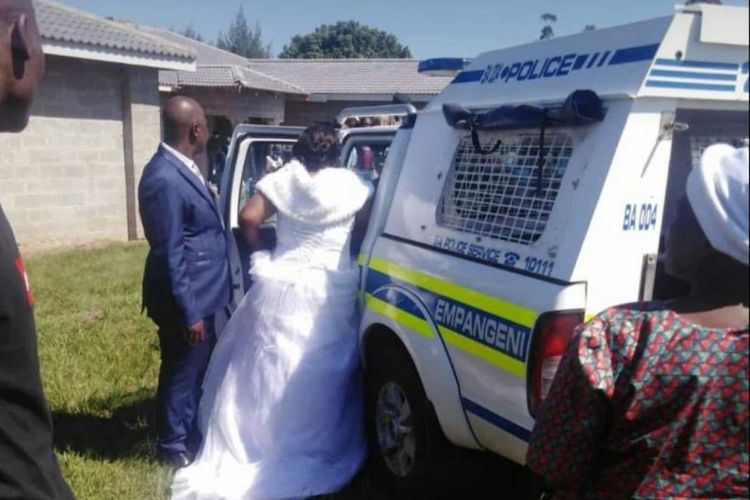 Jabulani Zulu membantu istrinya, Nomthandazo Mkhize, untuk naik ke mobil polisi. Mereka ditangkap karena tetap menikah di tengah lockdown mencegah virus corona.