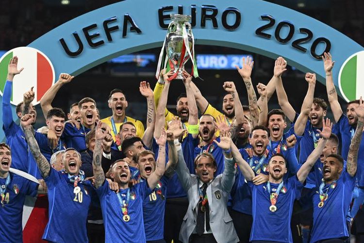 Timnas Italia di bawah asuhan pelatih Roberto Mancini mengangkat trofi Euro 2020 di podium usai mengandaskan perlawanan Inggris di Stadion Wembley pada babak final, Minggu (11/7/2021). Terkini, Italia bersama Turkiye terpilih menjadi tuan rumah Euro 2032.