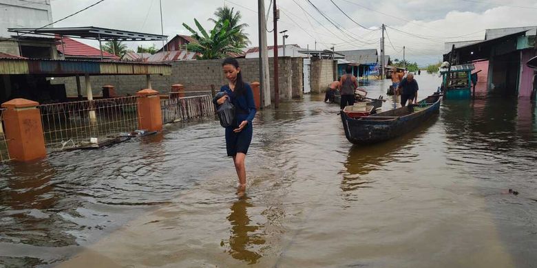 Seorang wanita muda warga Desa Hutadaa membawa barang berharganya meninggalkan rumahnya untuk mengungsi ke tempat yang lebih aman setelah air Danau Limboto meluap. Banyak rumah warga yang terendam hingga ketinggian dada orang dewasa.