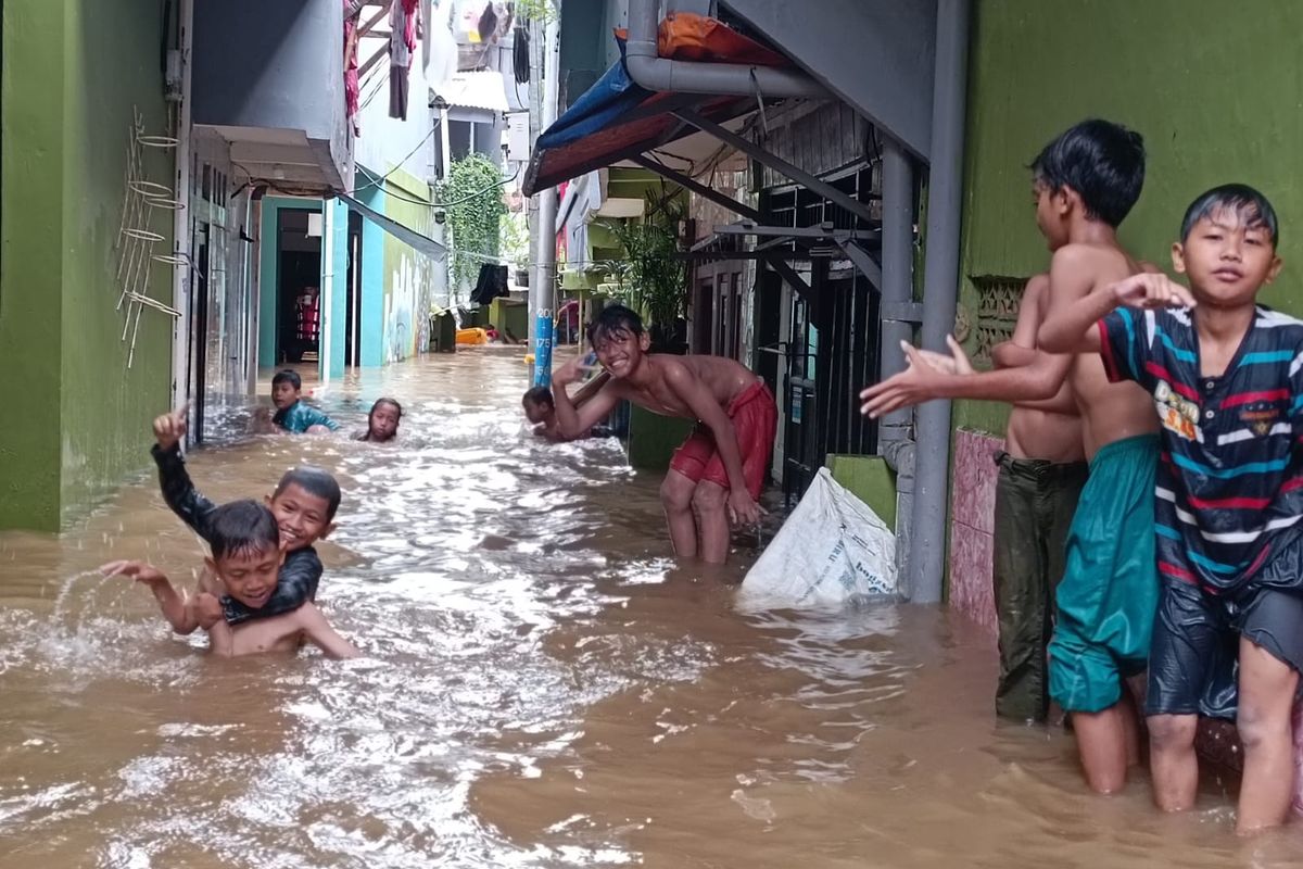Beberapa anak di kawasan RW 04 dan RW 05 Kelurahan Kampung Melayu, Kecamatan Jatinegara, Jakarta Timur, memanfaatkan genangan banjir sedalam sekitar 1 meter untuk berenang dan bermain air, Senin (27/2/2023).
