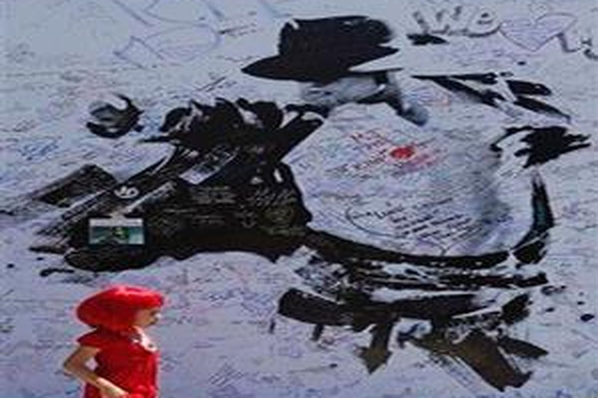 Seorang anak melintas di depan poster raksasa memuat gambar Michael Jackson, di Staples Center, Los Angeles, 5 Juli 2009 