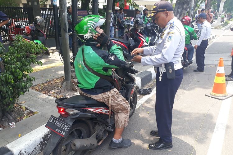 Petugas Suku Dinas Perhubungan Jakarta Timur menilang pengemudi ojek online yang parkir di jalur sepeda, Jalan Pemuda, Jakarta Timur, Kamis (21/11/2019).