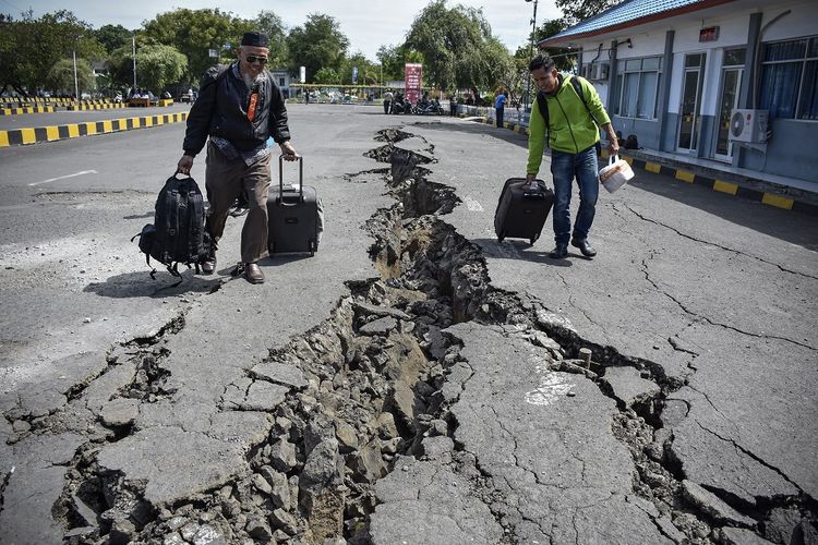 Sejumlah orang melintas di areal parkir ruang tunggu yang retak akibat gempa, di Pelabuhan Kayangan, Lombok Timur, NTB, Senin (20/8). Retakan areal parkir sedalam sekitar 1 meter tersebut akibat gempa bumi yang berkekuatan 7 Skala Richter yang mengguncang Lombok pada Minggu malam pukul 22.56 Wita. 