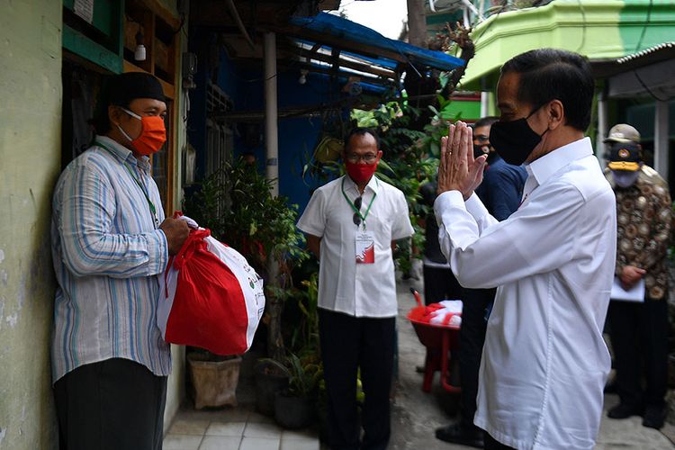 Presiden Joko Widodo (kanan) memberi salam kepada warga saat meninjau proses distribusi sembako tahap ketiga bagi masyarakat kurang mampu dan terdampak COVID-19 di kawasan Johar Baru, Jakarta Pusat, Senin (18/5/2020). Dalam blusukan ini, Presiden Jokowi ingin mengecek langsung penyaluran sembako pada masyarakat setempat.