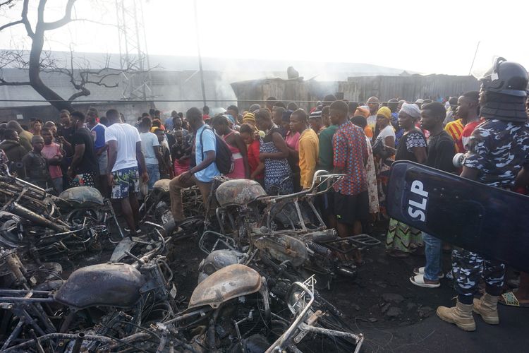 Warga berkerumun di sekitar bangkai sepeda motor yang hangus terbakar akibat ledakan tangki bensin di Freetown, ibu kota Sierra Leone, Sabtu (6/11/2021). Tangki bensin meledak di PMB Wellington Industrial Estate, timur Freetown, Jumat (5/11/2021), yang menewaskan lebih dari 90 orang.