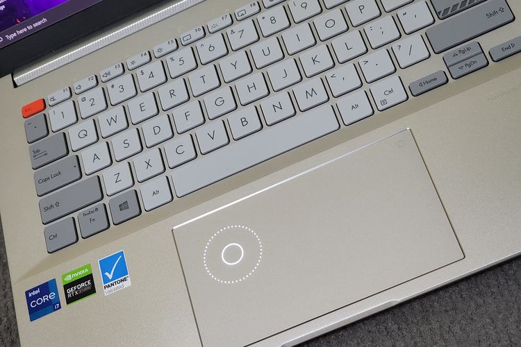 Tampilan keyboard dan fitur Asus DialPad di trackpad Vivobook Pro 14X OLED. Papan ketik laptop ini tampil mentereng dengan aksen warna ganda yang memberikan kesan futuristik. Tombol Esc, misalnya dihiasi dengan warna kuning, berbeda dengan deretan tombol huruf dan angka yang berwarna abu-abu terang, serta tombol Tab, Caps Lock, Shift, dan lain sebagainya yang berwarna abu-abu gelap. 
Di bagian bawah keyboard, terdapat trackpad yang memiliki fitur Asus DialPad. Fitur tersebut bisa ditampilkan pengguna dengan menyentuh dan menggeser ikon lingkaran yang terletak di pojok kanan atas trackpad. 