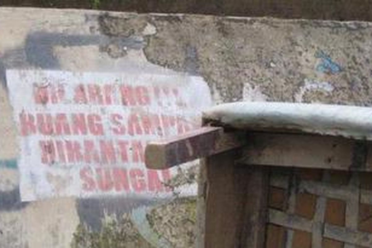 Tulisan berisi larangan membuang sampah di bantaran kali yang tertera di tembok tanggul Kali Bekasi di wilayah Perumahan Kemang Ifi Graha, Jatirasa, Kecamatan Jatiasih.