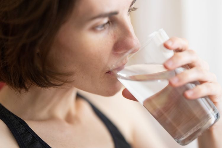 Ilustrasi minum air putih yang bisa menjadi salah satu cara mengatasi pilek secara alami.