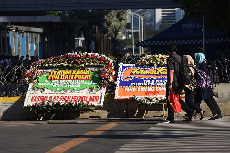 Pekerja melintas di dekat karangan bunga yang bertuliskan ucapan apresiasi bagi TNI dan Polri di depan gedung Bawaslu, Jalan MH Thamrin, Jakarta, Jumat (24/5/2019). Warga mengirim karangan bunga tersebut sebagai wujud apresiasi bagi TNI dan Polri dalam menjaga ketertiban dan keamanan pascapengumuman penetapan hasil rekapitulasi Pemilu serentak 2019.