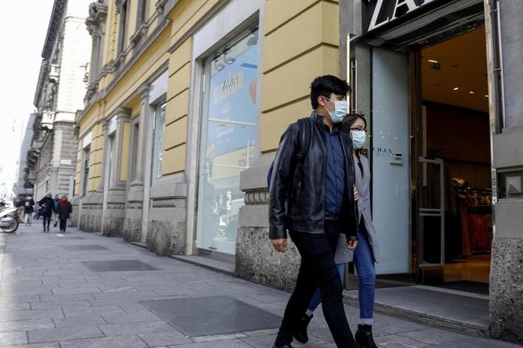 Seorang pria dan wanita berjalan memakai masker di depan gerai ZARA di Corso Buenos Aires, sebuah jalan yang berisi banyak toko-toko ternama di Milan, Italia. Foto diambil pada 10 Maret 2020.
